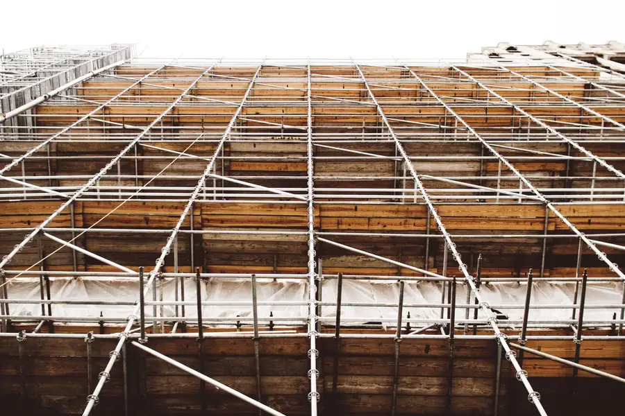 Scaffold frame and boarded lifts rising against a bright sky, the kind of access a commercial solar installation needs