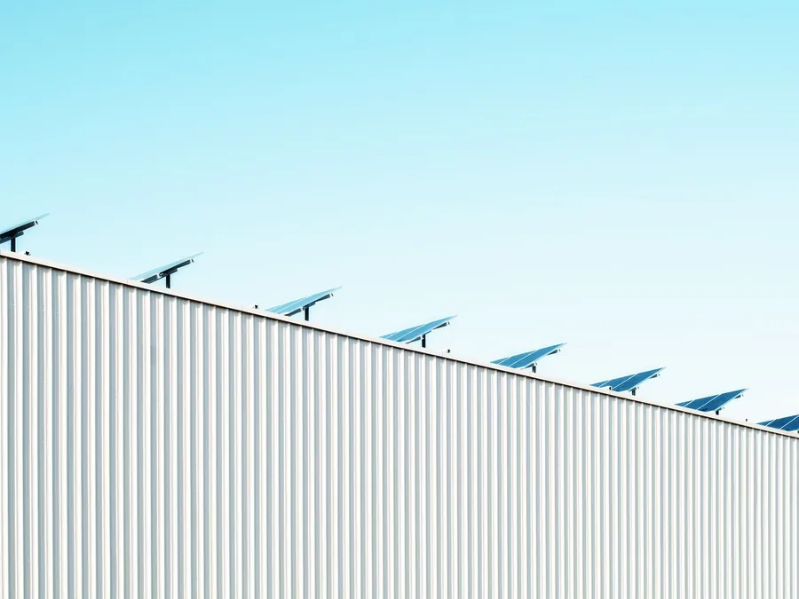 Solar panels on frames along the top of a building clad in profiled metal sheeting